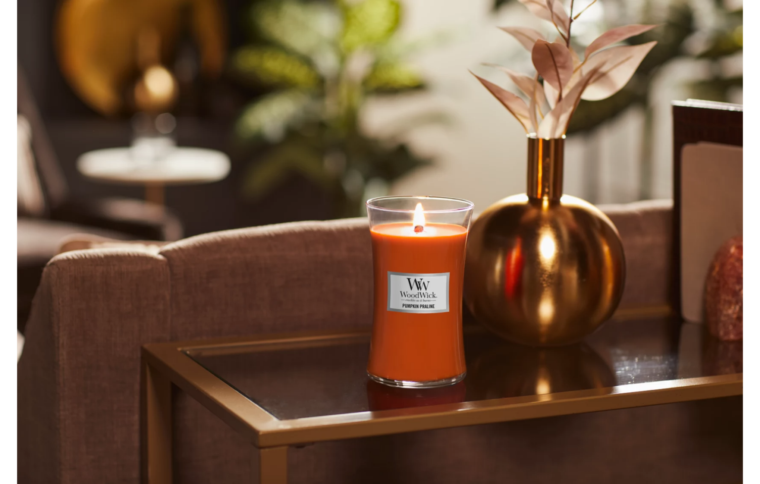 Orange ljus från WoodWick på bord.